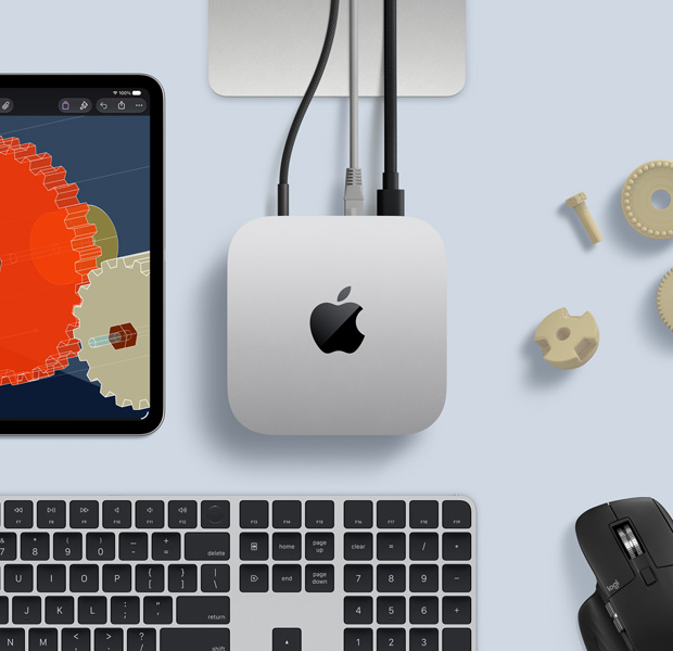 iPad menampilkan objek STEM mendetail, Mac mini berada di tengah dengan kabel daya terpasang, dudukan Studio Display terlihat sebagian, terhubung melalui USB-C, Magic Keyboard dengan Touch ID, dan mouse Logitech